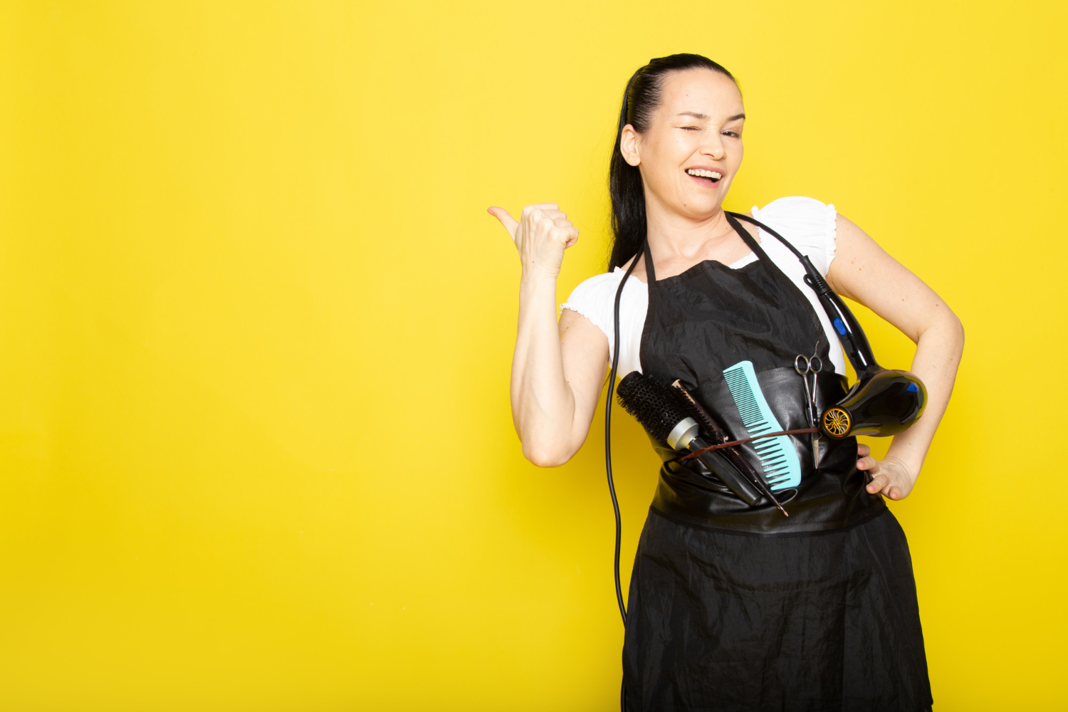 front-view-young-female-hairdresser-white-t-shirt-black-cape-with-brushes-hairdryer-smiling-welcoming-posing